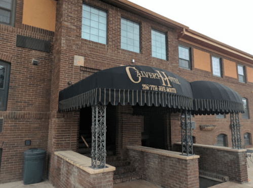 Entrance of the Calvert Hotel featuring a black awning and brick facade.